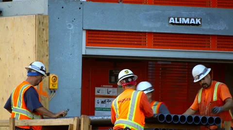 Construction workers unload pipes at new development site Stock Footage 34134962