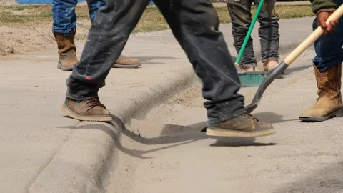 Construction workers use a shovel and broom to clean dirt off the street, Stock Footage 142553158