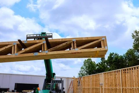Construction workers use telehandler lift to place wooden beams at building.. Stock Photos