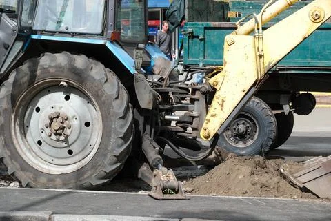 Construction workers use a tractor to dig up pavement in a city Stockfoto's