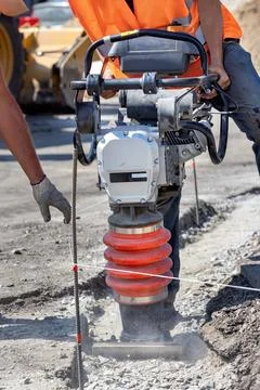 Construction workers using a compactor to prepare ground for building site .. Stock Photos