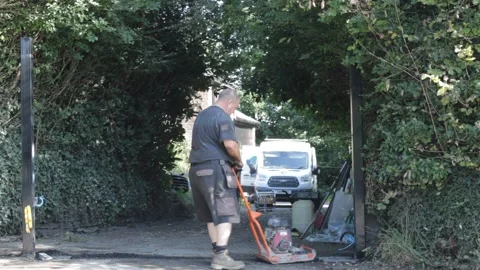 Construction workers using heavy machinery in a domestic UK driveway Vídeo Stock 160407766