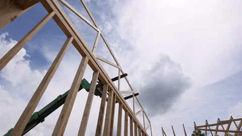 Construction workers using telehandler machinery to lift wooden beams at Stock Footage 309786871