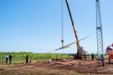 Construction workers using a truck crane lift the rotor of a wind turbine Stock Photos