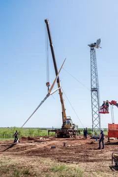 Construction workers using truck crane lift the rotor of wind turbine Stock Photos