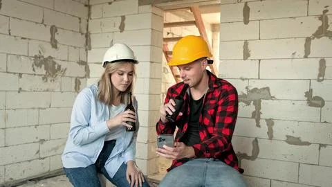 Construction workers viewing smartphone content over beer during work break Stock Photos