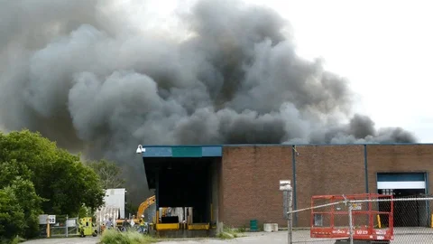 Construction workers walking in foreground of a large fire sending smoke up Vidéo 97683660