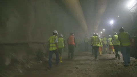 Construction workers walking out from a dark smoke filled tunnel Stock Footage 92185504