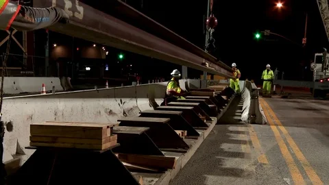 Construction workers work on a freeway overpass in time lapse at night in Los Stockbeeldmateriaal 75698048