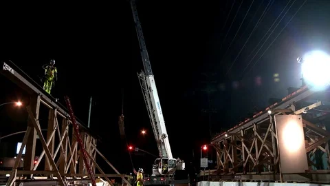 Construction workers work on a freeway overpass at night in Los Angeles. 库存影片 75698068
