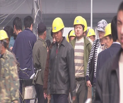 Construction workers in yellow helmets and other pedestrians pass camera Stock Footage 86744026
