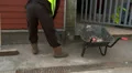 Construction working putting swept debris into wheel barrow HD Footage