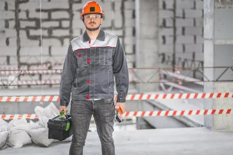 Construction workman ready for renovation work. Builder in uniform carrying Stock Photos