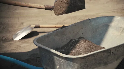 Construction works. A worker pours crushed stone into a cart with a shovel Stock Footage 155216898