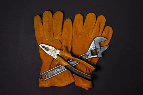 Construction yellow gloves with tools on a black background.  Stock Photos
