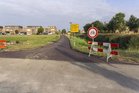 Construction zone road with red and white barriers, yellow warning sign Foto stock