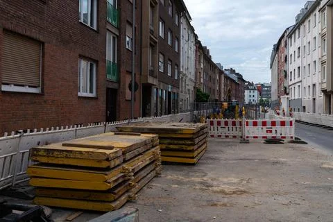Construction zone with stacked wooden planks and road barriers in urban setting Stock Photos