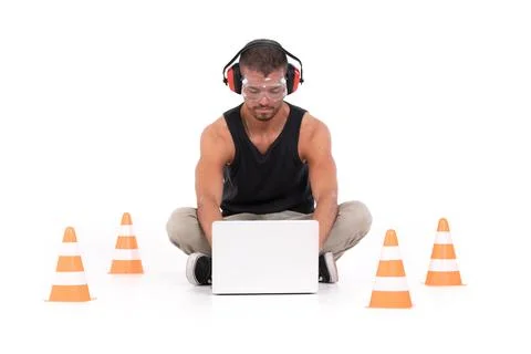 Constructor man working with a laptop within a delimited area with orange cones Stock Photos