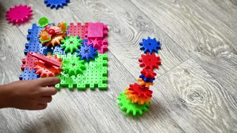 Constructor toy with colorful plastic gears arranged on floor while child hand Vídeos de archivo 335389421