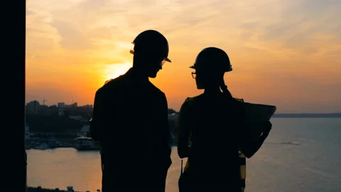 Constructors look at a city on a sunset background, back view. Vídeos de archivo 95038895