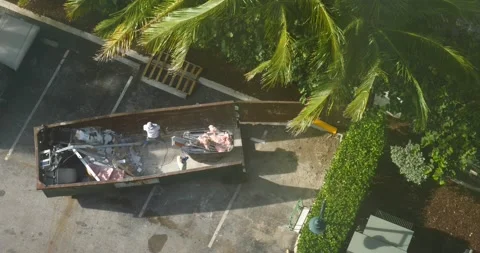 Constructure workers throwing debris into dumpster during remodel top view Ariel Stock Footage 213385347