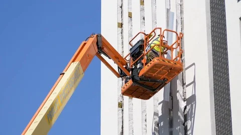 Construnction worker on a platform to work on the façade on a building Stock Footage 78079104