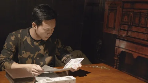 Consufused boy reading the map on a wood table of dark room Video stock 103402464