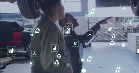 Consultant in garage tapping tablet showing digital icons guiding colleague Stock Footage 312694970
