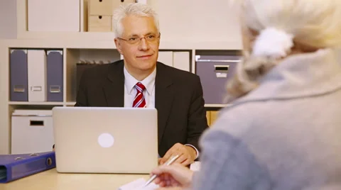 Consultant talking to elderly customer in office Video stock 34625031