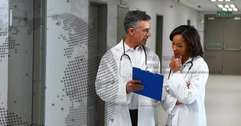 Consulting two doctors in lab coats holding blue clipboard in corridor by dot Stock Photos