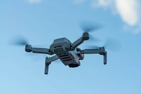 Consumer drone with camera hovering against sky Stock Photos