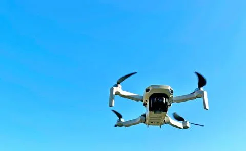 Consumer drone with camera hovering against sky Stock Photos