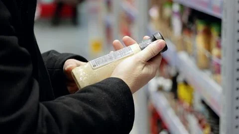 Consumer examining condiment label, comparing nutritional details while Stock Photos
