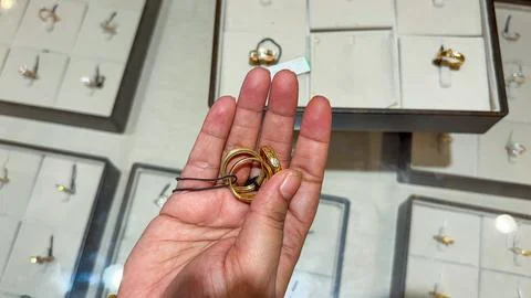 Consumer hands examining different styles of yellow gold bands Stock-Fotos