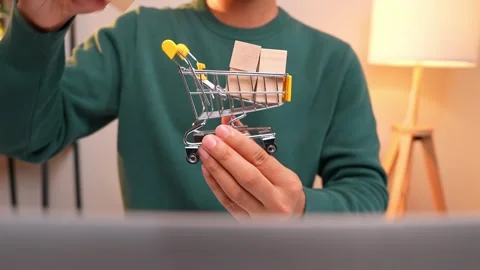 A consumer places wooden blocks into a tiny shopping cart. Video stock 317075907