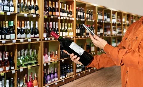 Consumer scanning e-label on wine bottle in liquor store. Stock Photos