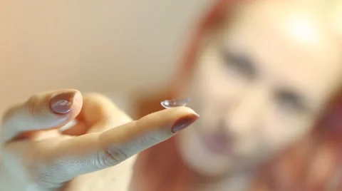 Contact lens: Young woman holding contact lens on finger in front of her eye Stock Footage 59643476