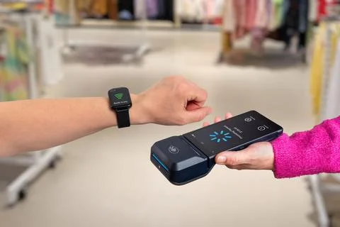 Contactless payment using smart watch and mobile POS terminal inside retail.. Stock Photos