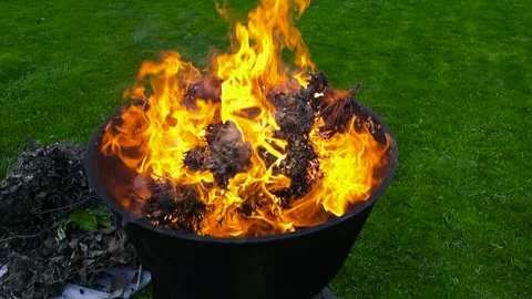 Contained fire burning in a metal fire pit in a garden Stock Footage 337869469