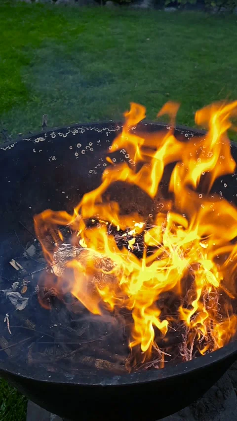 Contained Fire Burning in a Metal Fire Pit at Dusk Stock Footage 338994371