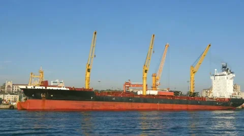 Container cargo freight ship being loaded with large deck cranes in shipyard Stock Footage 49869498