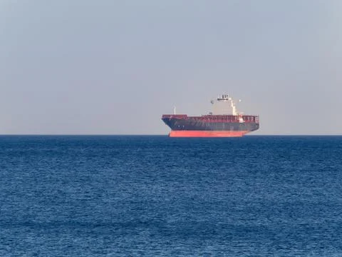 Container  cargo ship anchored off the harbor awaiting  loading Stock Photos