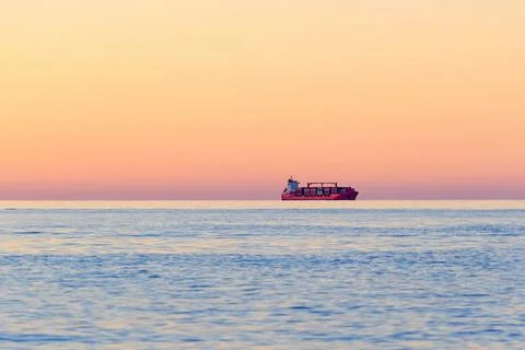 Container Cargo ship on the horizon at sunset. Stock Photos