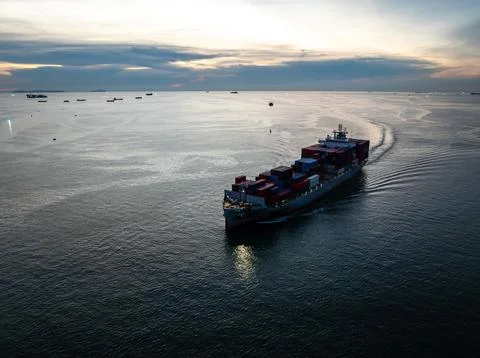 Container Cargo Ship Sailing Across Ocean At Sunset In Si Racha Thailand El.. Fotos de archivo