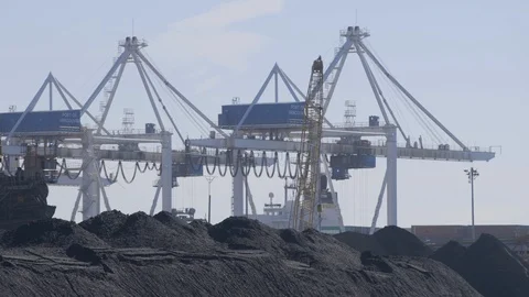 Container cranes moving in background, coal piles in foreground Stock Footage 103347785