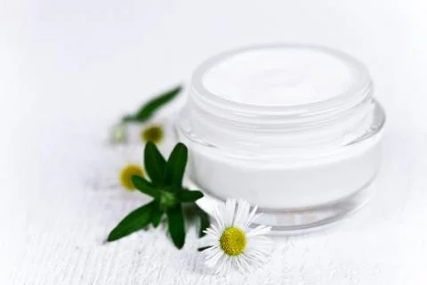 Container with cream and chamomiles Foto stock