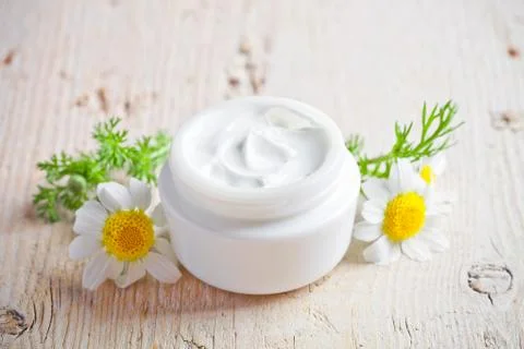 Container with cream and chamomiles Stock Photos