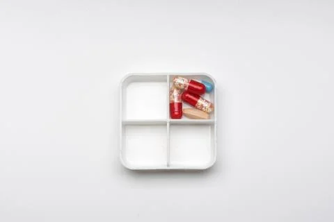 Container with different capsules and tablets on a white background, concept Stock Photos