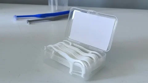 A container of flossers on a table close-up, with an irrigator and toothbrushes Stock Footage 329969428