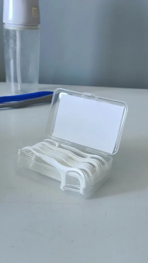 A container of flossers on a table close-up, with an irrigator and toothbrushes Vidéo 329969432
